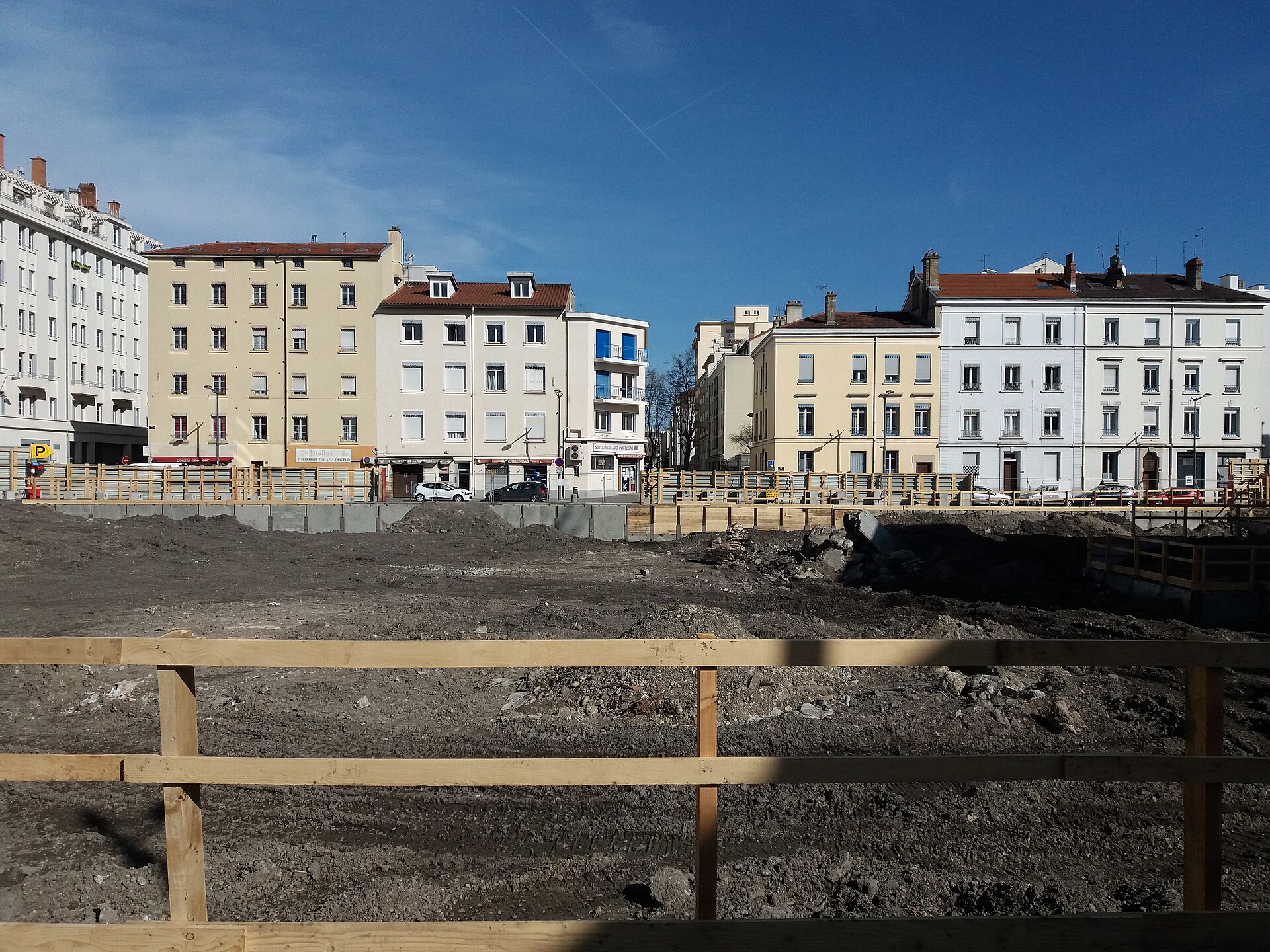 Chantier de démolition à Lyon, entouré de palissades devant des immeubles